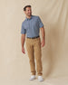 Men's Don Ho Polo in New Indigo, full length front view on model featuring a navy base with an all-over light blue floral print, paired with khaki pants, a dark leather belt, and white shoes