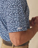 Men's Don Ho Polo in New Indigo, close-up sleeve view on model highlighting the Straight Down logo patch on the sleeve hem and the all-over light blue floral print on a navy base