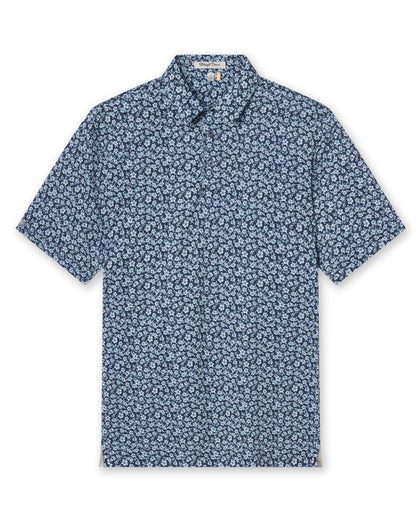 Men's Don Ho Polo in New Indigo, flat lay front view featuring a navy base with an all-over light blue floral print, with Straight Down logo patch visible on sleeve