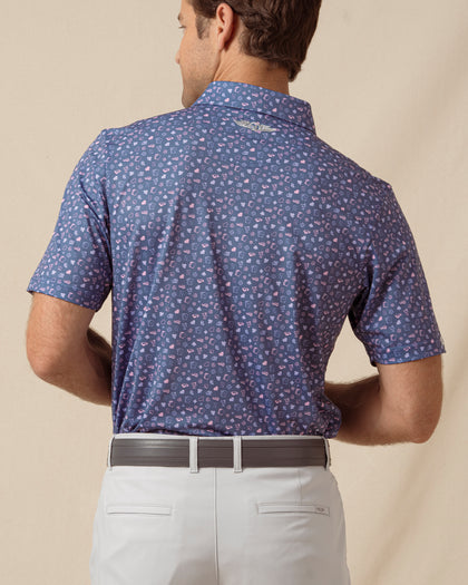 Back view of men’s blue printed polo with allover card and icon pattern, paired with light gray shorts