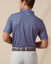 Back view of men’s blue printed polo with allover card and icon pattern, paired with light gray shorts