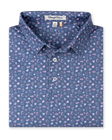 Men's Hold Em Polo in Moonlight, folded flat lay front view featuring an allover casino-themed print with playing cards, card suits, poker chips, dice, and cocktail glasses in pink and lavender on a slate blue base