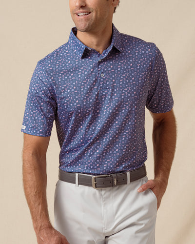 Men’s blue polo with allover playing card–inspired print, paired with light gray shorts and belt