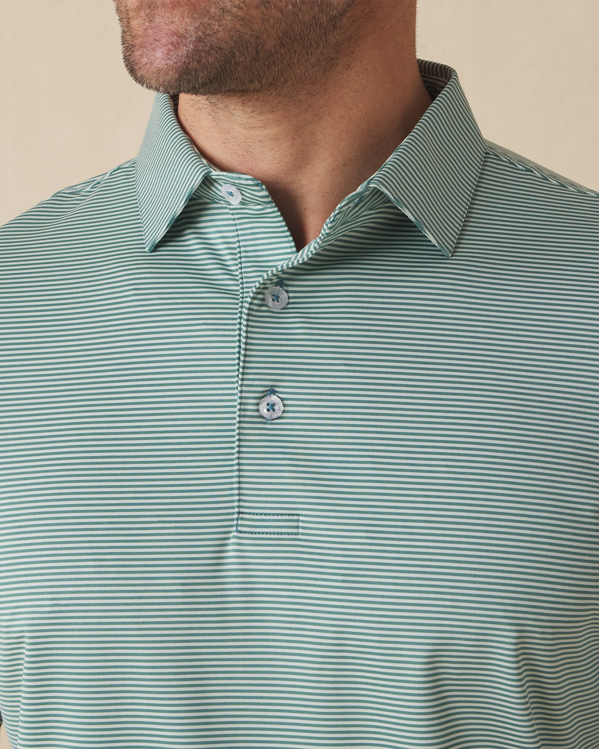 Men's Peninsula Stripe Polo in Celery, close-up detail view on model featuring a green and white micro stripe pattern and Straight Down logo engraved buttons