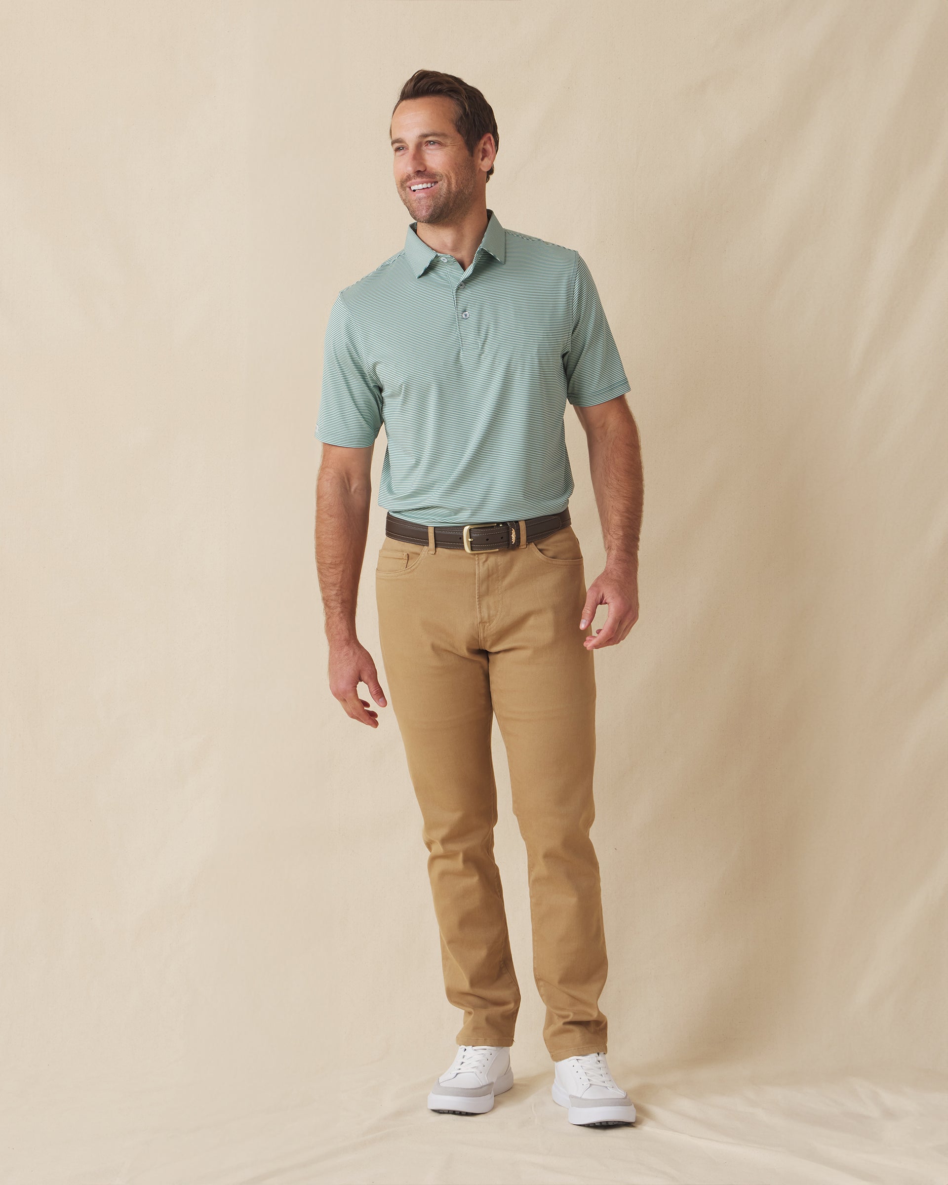 Men's Peninsula Stripe Polo in Celery, full-length front view on model featuring a green and white micro stripe pattern, paired with khaki pants and white golf shoes
