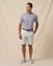 Men’s navy and white striped performance polo styled with light gray shorts and casual sneakers
