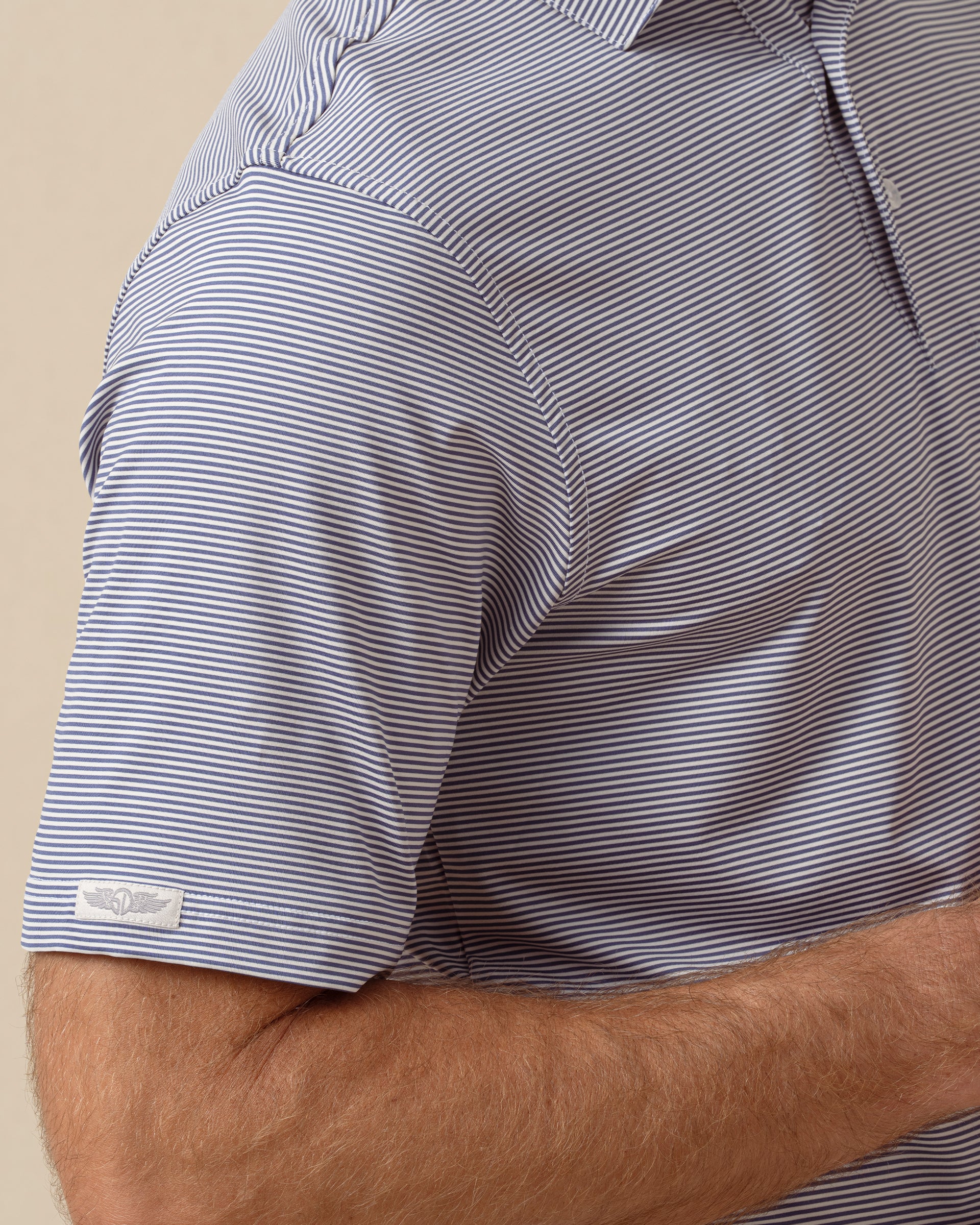 Close-up of men’s striped performance polo sleeve with subtle logo detail