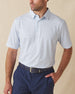 Men's Wilshire Polo in Gemstone, front view on model featuring a white base with an all-over blue geometric micro print, paired with navy pants and a dark leather belt