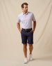 Men’s polo with two-tone geometric print in haze, styled with navy shorts, brown belt, and white sneakers