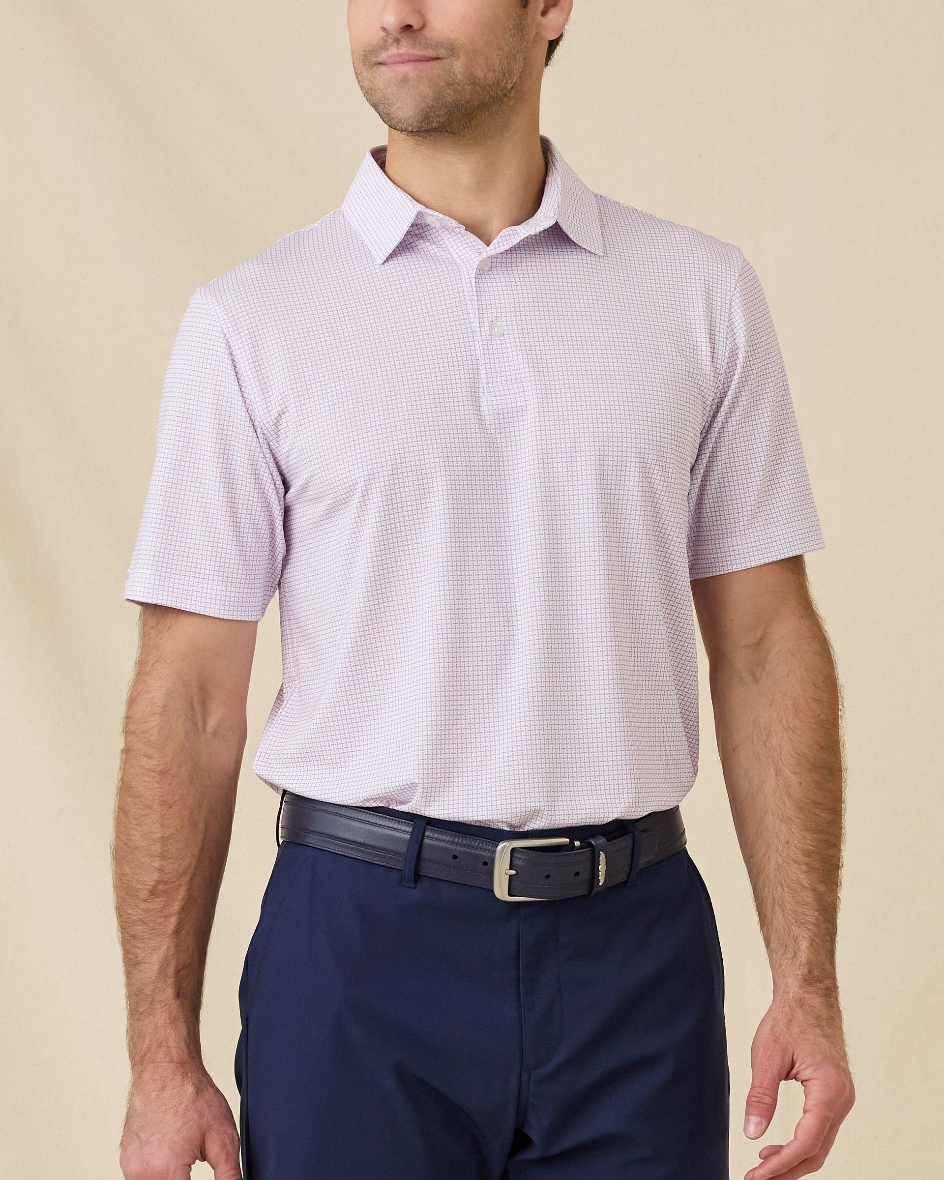 Model wearing the Wilshire Polo in Punch, a performance golf polo with a subtle geometric print