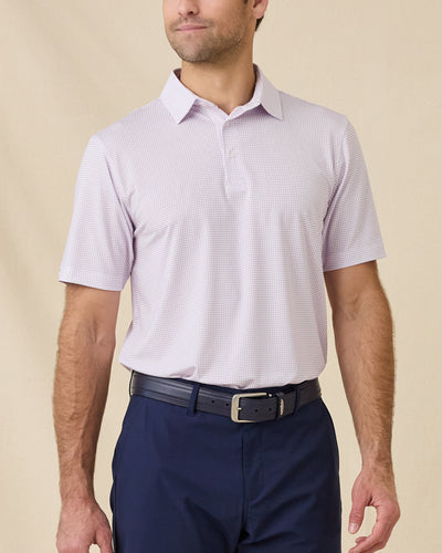 Model wearing the Wilshire Polo in Punch, a performance golf polo with a subtle geometric print