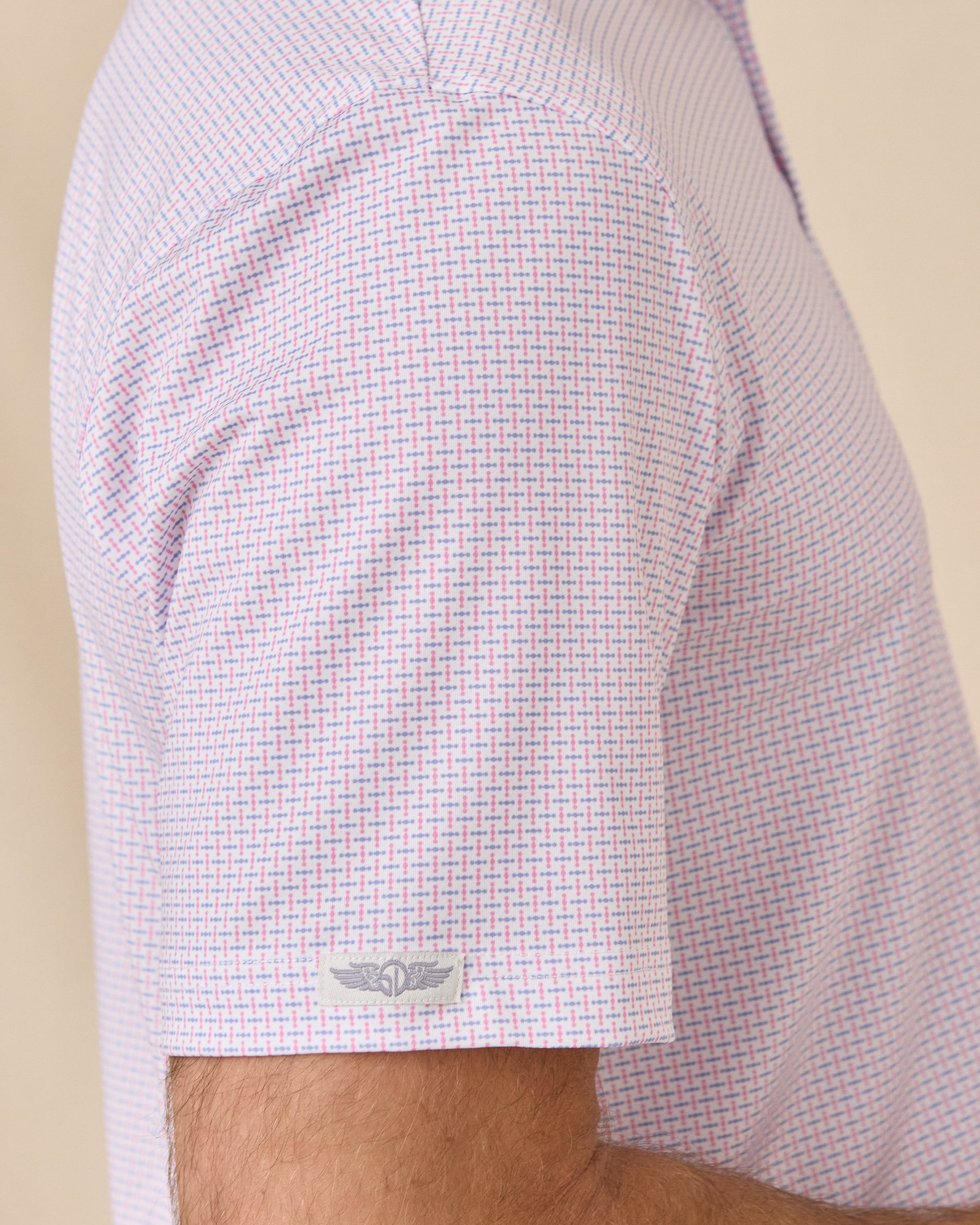 Sleeve detail of the Wilshire Polo in Punch showing the geometric print and Straight Down logo tab