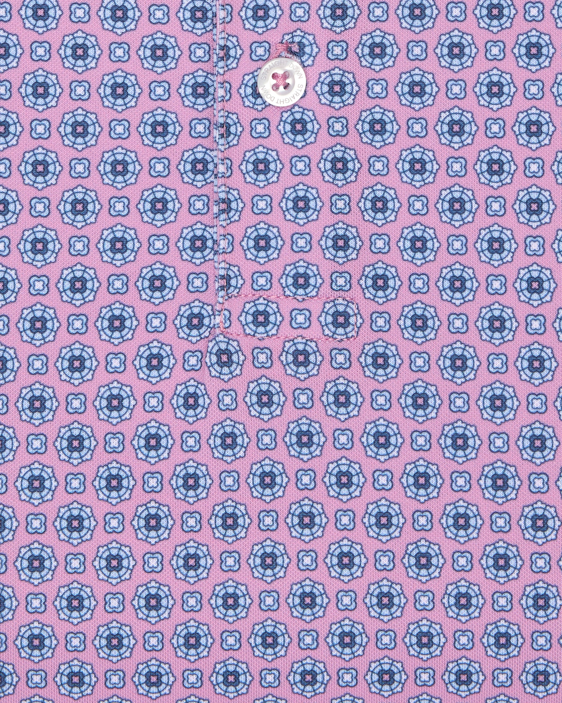 Close-up of pink golf polo with blue geometric print and button detail