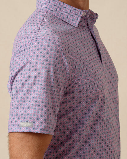 Close-up of men’s haze purple polo featuring a small-scale geometric medallion print and sleeve logo detail