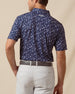 Back view of men’s navy floral print polo with allover pattern, paired with light gray shorts