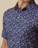 Close-up of navy polo shirt featuring small white floral print, button placket, and structured collar