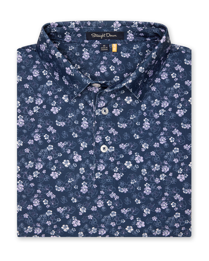 Men's Dogwood Polo in New Indigo, folded flat lay front view featuring an allover floral dogwood blossom print in lavender and white on a navy base