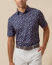 Men’s navy polo with allover floral print, styled with light gray shorts and a belt