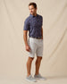 Men’s navy floral print polo shirt paired with light gray shorts, belt, and gray sneakers