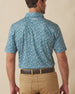 Men's Dogwood Polo in Sage, back view on model featuring a sage green base with a scattered white and lavender floral print and Straight Down logo embroidered at upper back, paired with khaki pants