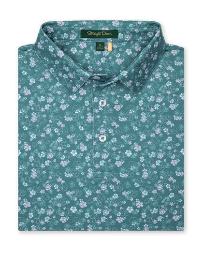 Men's Dogwood Polo in Sage, folded flat lay front view featuring an allover floral dogwood blossom print in lavender and white on a teal green base
