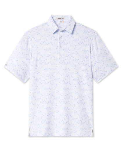 Front view of the South Beach Polo in Blue Shade, featuring a white base with an allover light blue print of palm trees, flamingos, buildings, cars, and coastal scenery.