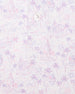 Men's South Beach Polo in Violet, close-up flat lay view featuring a white fabric with an all-over scenic print of palm trees, flamingos, and buildings in pink and lavender with a visible button placket detail