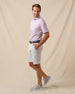Men’s haze floral print polo styled with light gray shorts, brown belt, and gray sneakers
