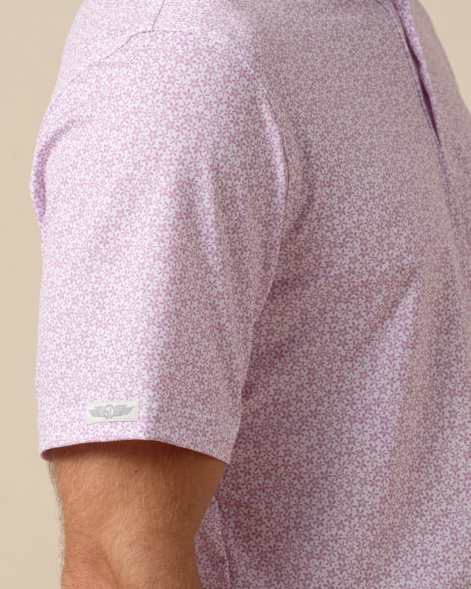 Close-up of men’s haze polo with subtle all-over floral print and short sleeve logo detail