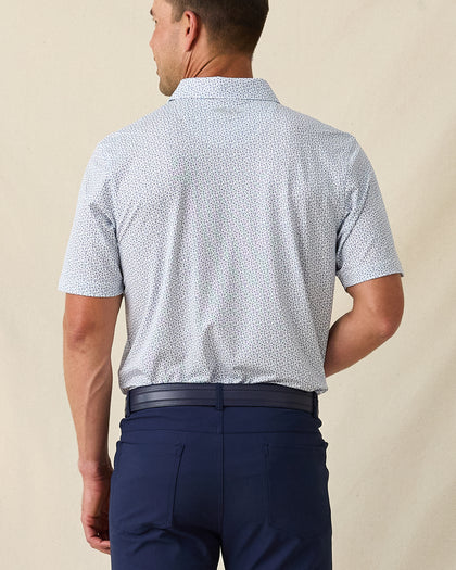 Men's Gin Therapy Polo in Pink Floyd, back view on model featuring an allover martini glass print in purple and light blue on white, paired with navy pants and a navy belt