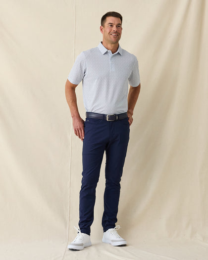 Men's Gin Therapy Polo in Pink Floyd, full length front view on model featuring an allover martini glass print in purple and light blue on white, paired with navy pants, a navy belt, and white golf shoes