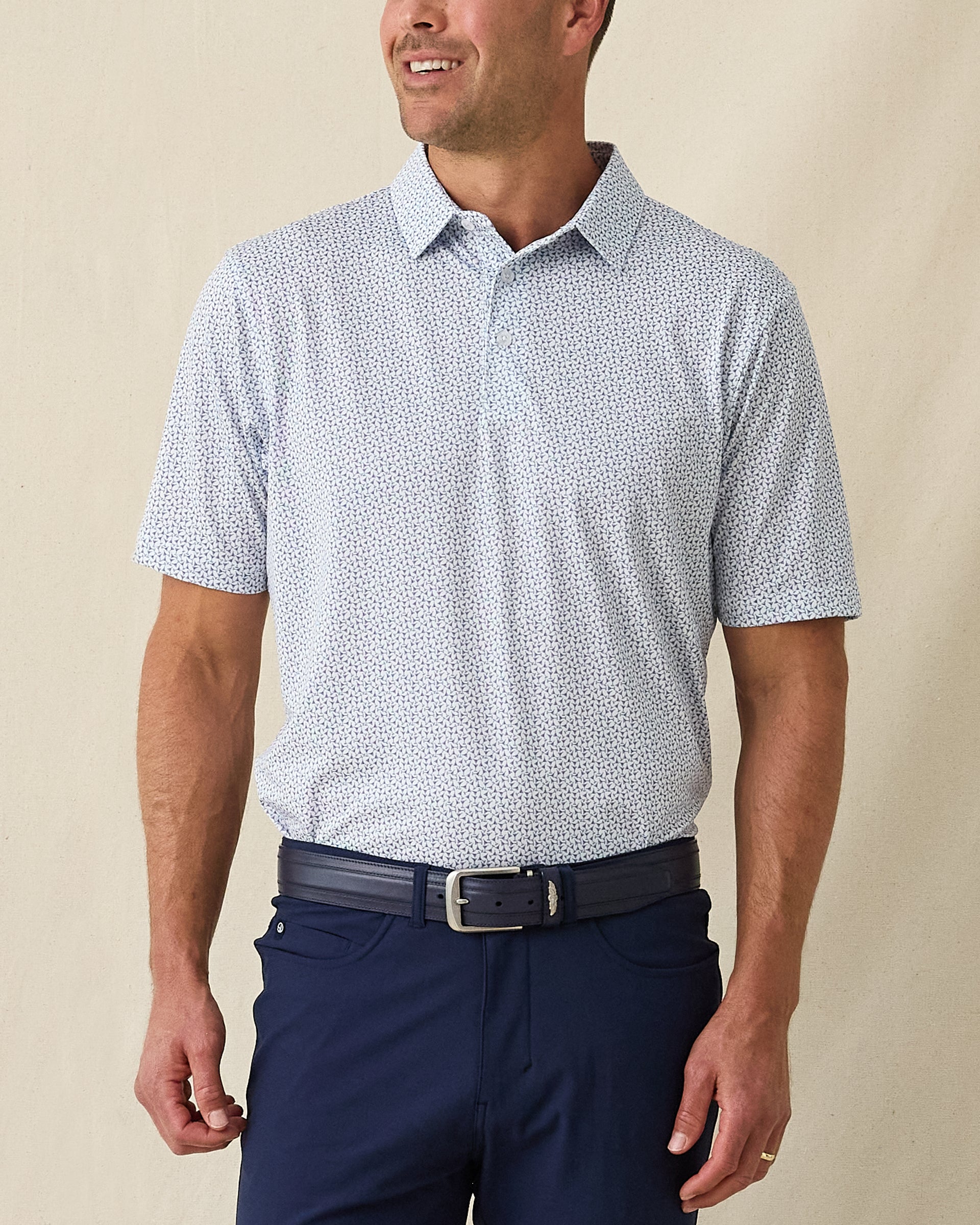 Men's Gin Therapy Polo in Pink Floyd, front view on model featuring an allover martini glass print in purple and light blue on white, paired with navy pants and a navy belt