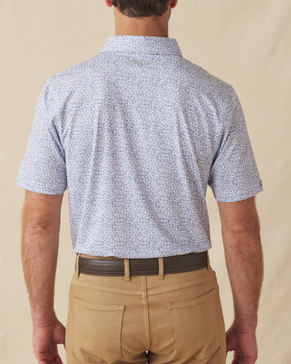 Men's Dog Pound Polo in Moonlight, back model view featuring a white short sleeve polo with an all-over scattered dog face and bone print in navy with the Straight Down logo at the back collar