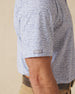 Men's Dog Pound Polo in Moonlight, close-up model view featuring the sleeve hem with the Straight Down logo tab detail on a white short sleeve polo with an all-over scattered dog face and bone print in navy