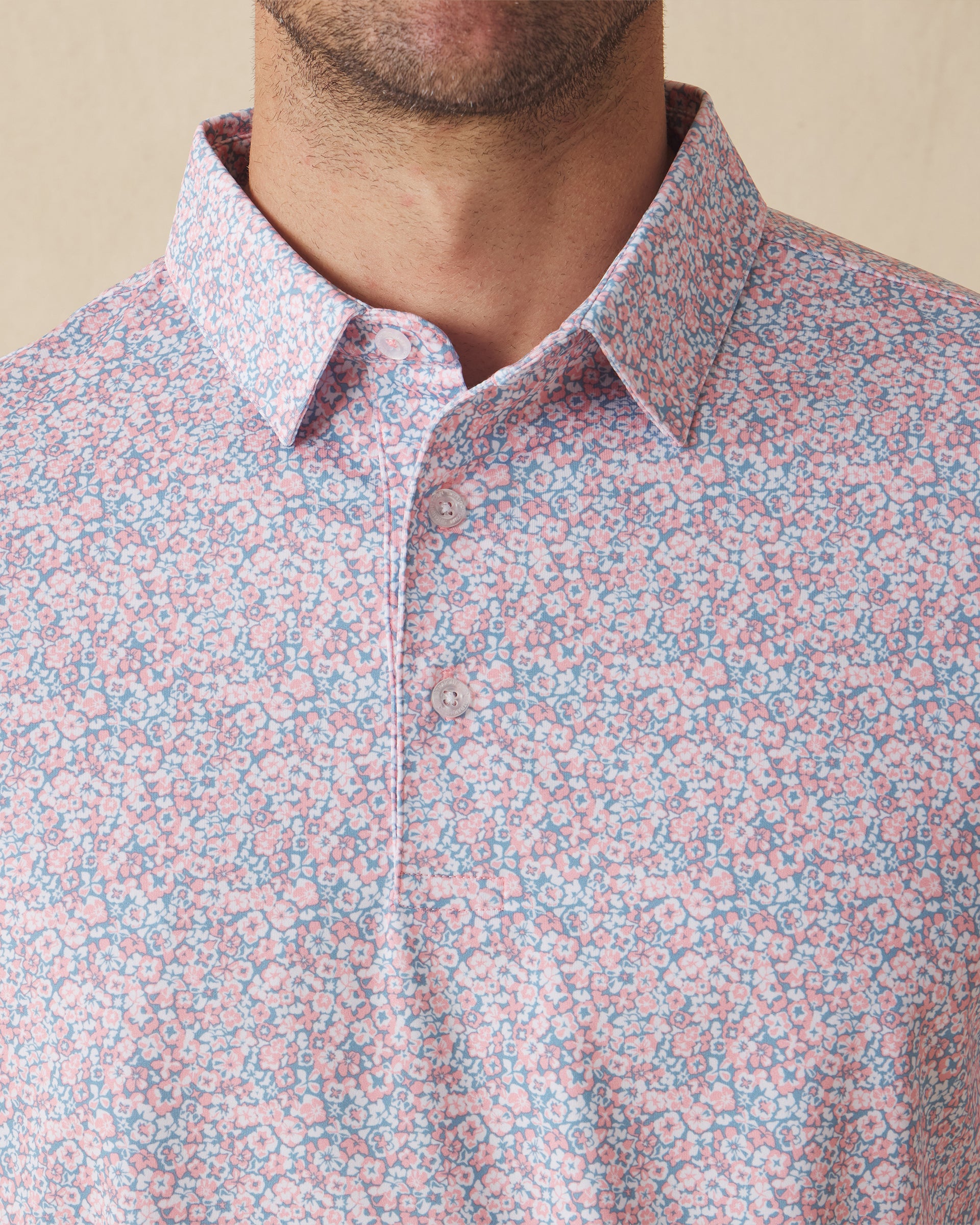 Men's Ocala Polo in Spritz, close-up front view on model highlighting the all-over pink floral print on a blue base