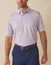 Men's Ocala Polo in Spritz, front view on model featuring a blue base with an all-over pink floral print, paired with navy pants and a dark leather belt