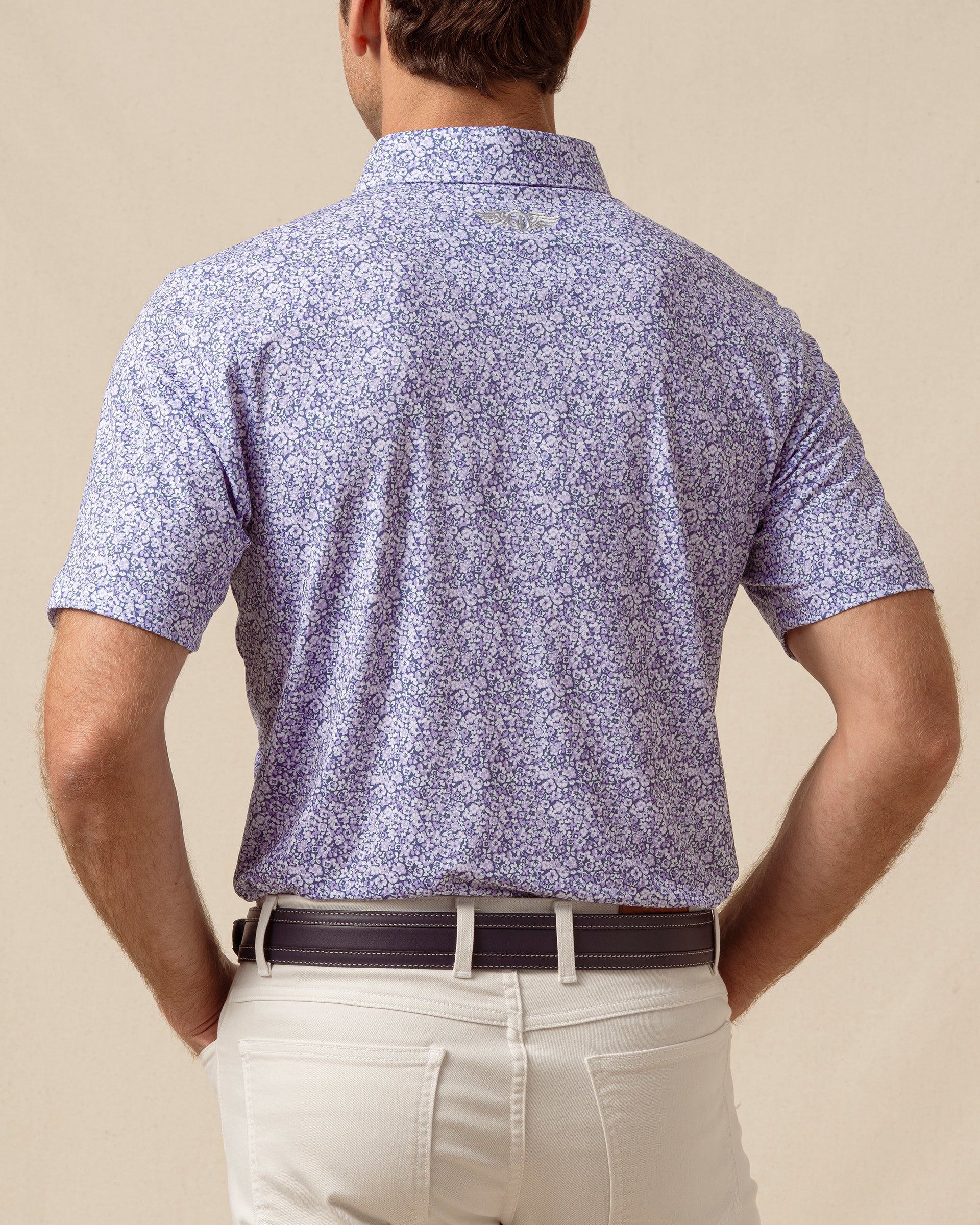 Back view of men’s light purple floral print polo shirt paired with light khaki pants and a belt