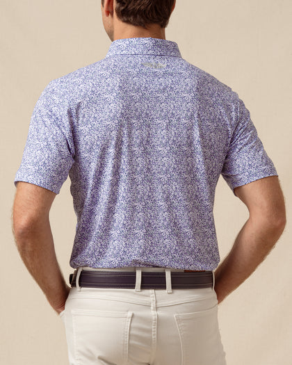 Back view of men’s light purple floral print polo shirt paired with light khaki pants and a belt