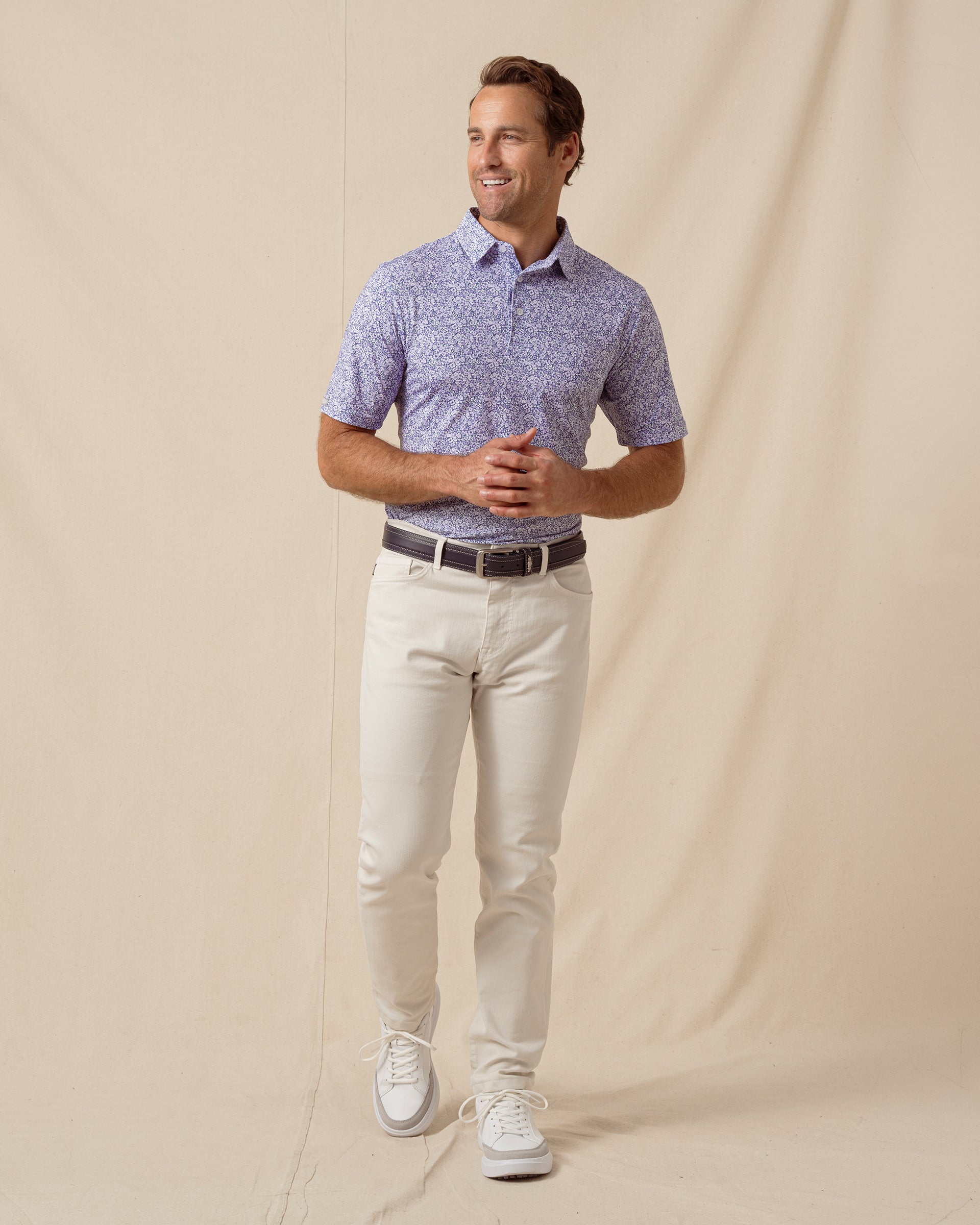 Men’s light purple floral print polo shirt paired with light khaki pants, belt, and white sneakers