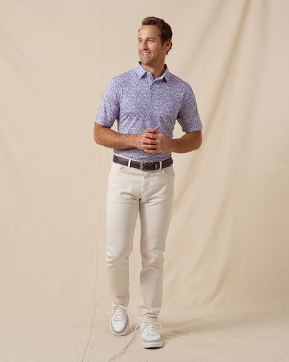 Men’s light purple floral print polo shirt paired with light khaki pants, belt, and white sneakers