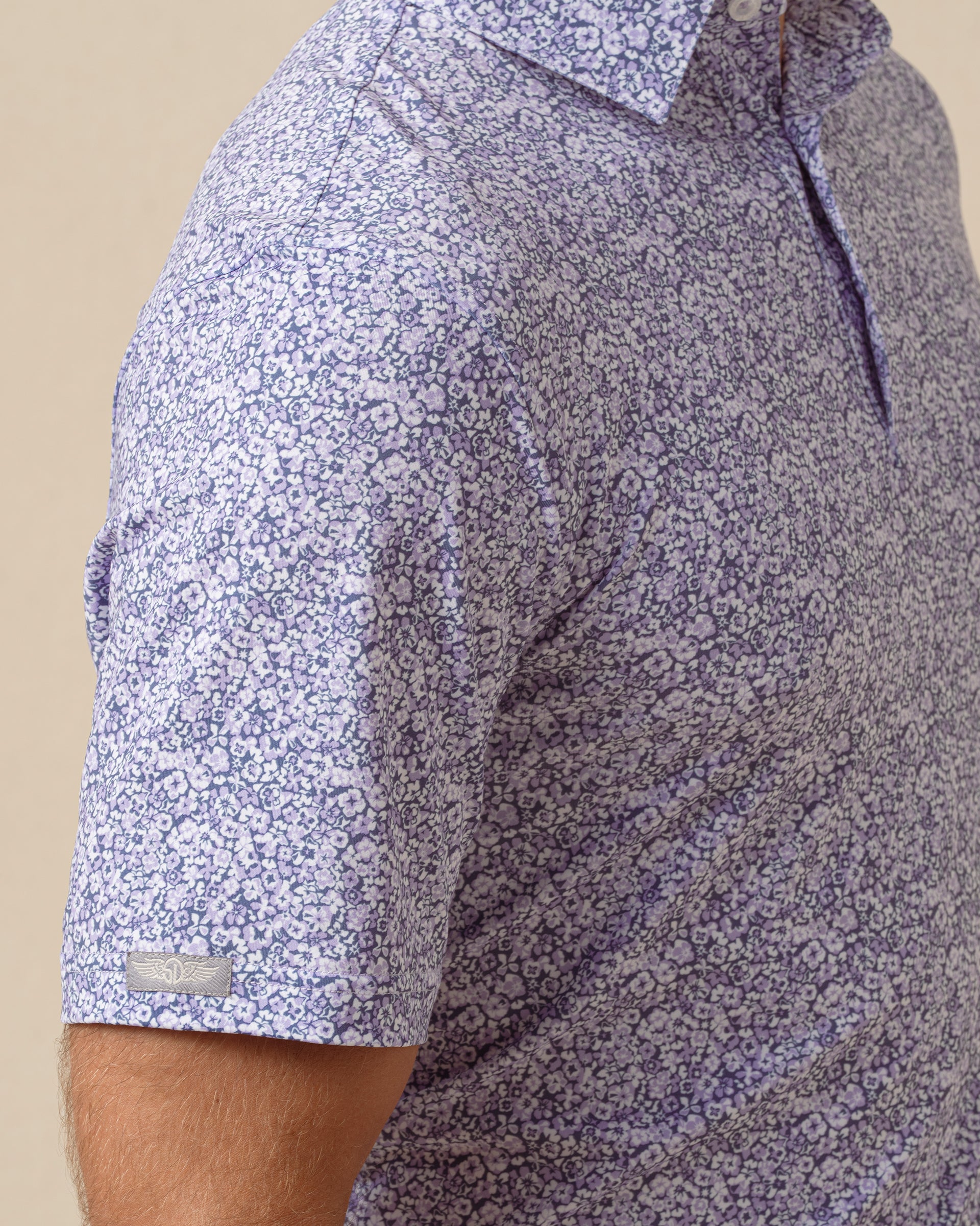 Close-up of light purple floral print polo sleeve showing detailed pattern and logo tag