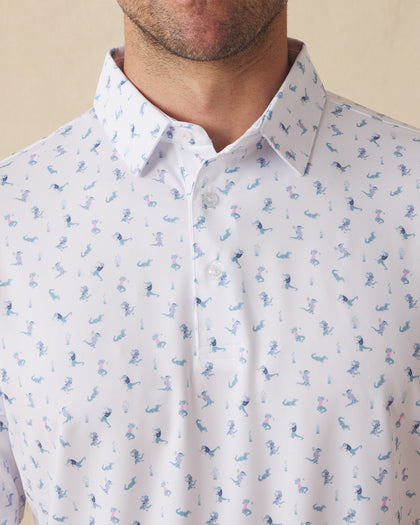 Men's Gators Polo in Violet, close-up model view featuring the collar and button placket detail of a white short sleeve polo with an all-over scattered golf-playing alligator print in blue and pink