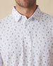 Men's Gators Polo in Violet, close-up model view featuring the collar and button placket detail of a white short sleeve polo with an all-over scattered golf-playing alligator print in blue and pink