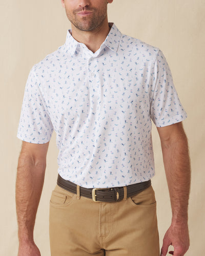 Men's Gators Polo in Violet, front model view featuring a white short sleeve polo with an all-over scattered golf-playing alligator print in blue and pink paired with khaki pants and a brown belt