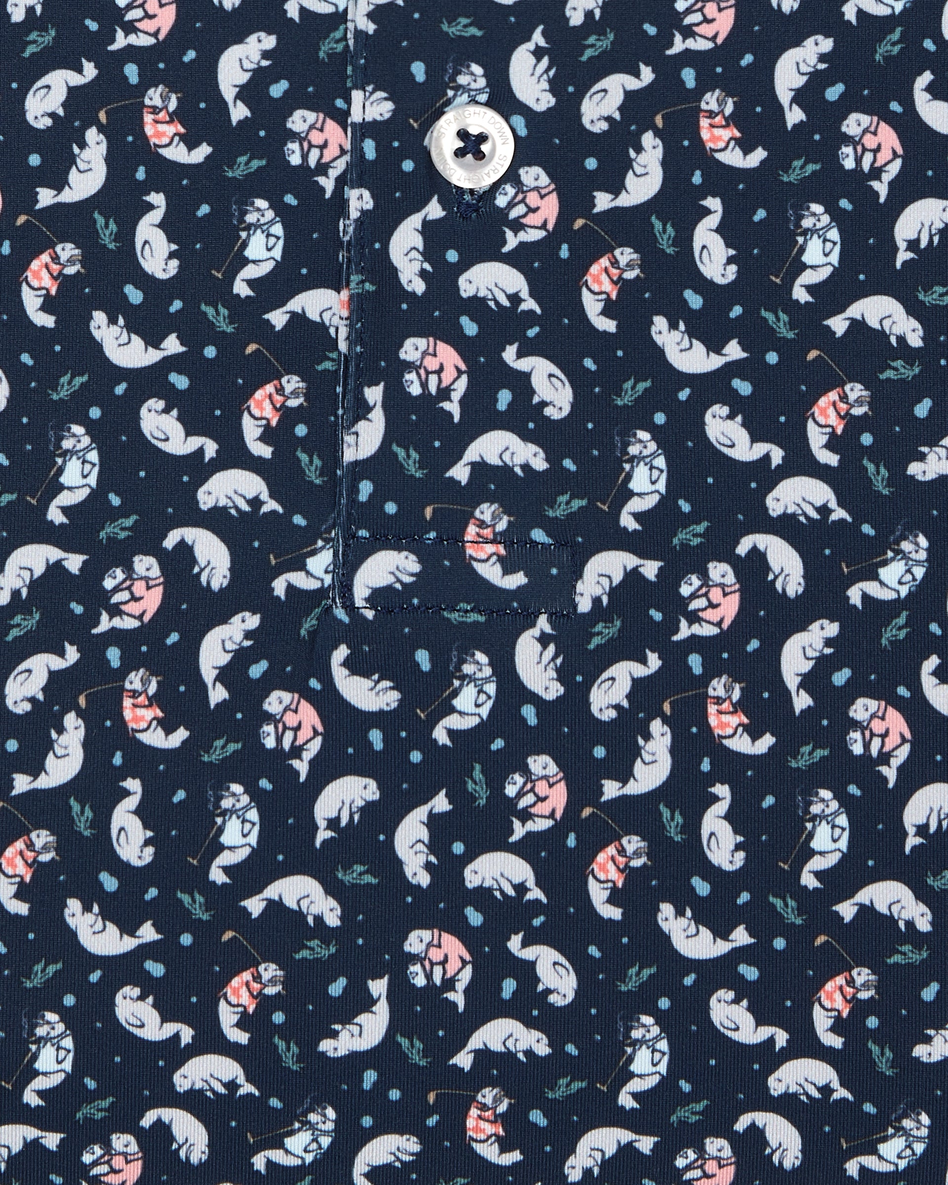 Men's Manatee County Polo in New Indigo, close-up flat lay view featuring a navy fabric with an all-over scattered golf-playing manatee print in white and pink with a visible button placket detail