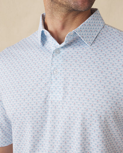 Men's Slam Dunk Polo in Coastal, close-up front chest detail featuring a button placket and an allover basketball hoop and ball print in light blue and pink on white