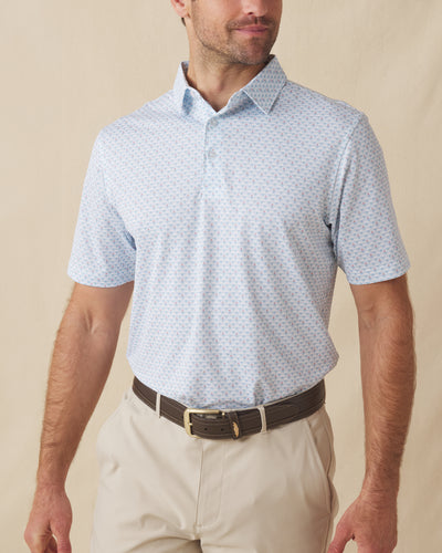 Men's Slam Dunk Polo in Coastal, front view on model featuring an allover basketball hoop and ball print in light blue and pink on white, paired with khaki pants and a brown belt