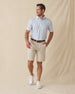 Men's Slam Dunk Polo in Coastal, full length front view on model featuring an allover basketball hoop and ball print in light blue and pink on white, paired with khaki shorts, a brown belt, and white golf shoes