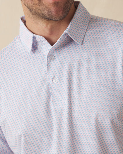 Men's Cocora Polo in Coastal, close-up front view on model highlighting the all-over blue and pink palm tree micro print on a white base