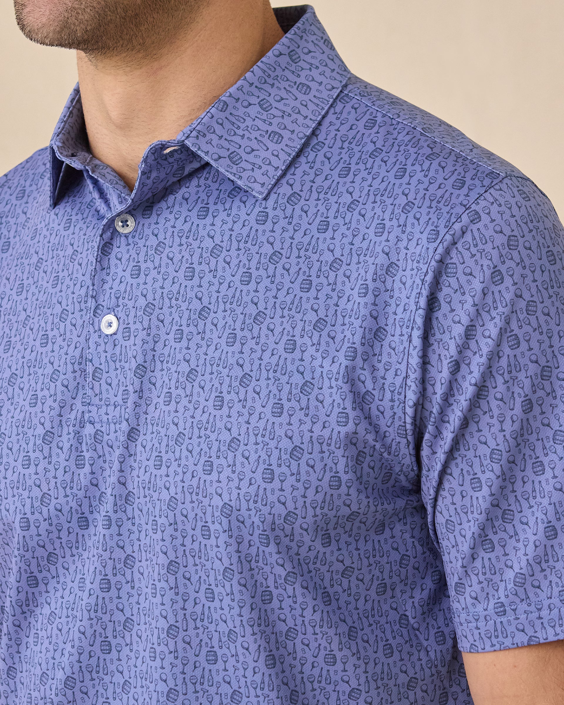 Close-up of the Tannins & Tees Polo in Tidal Blue showcasing the allover golf and wine-inspired print, self-collar, and three-button placket